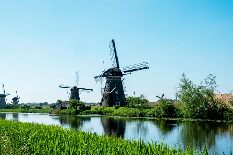 there are three windmills in the grass near water