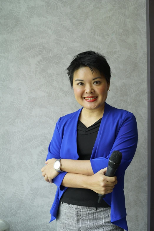 a woman in a blue jacket holds her arm crossed, standing behind her