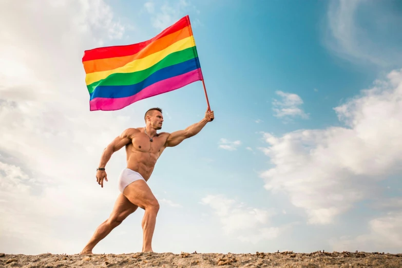 a man with a rainbow flag at the beach