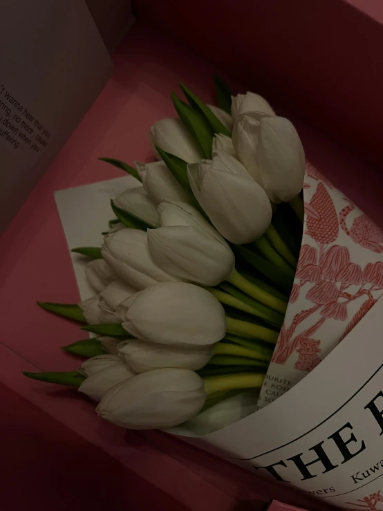 a bouquet of white tulips are displayed in a gift box