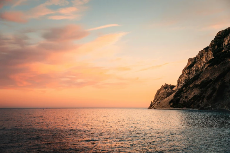 a ship is sitting on the water and rocks against the sky