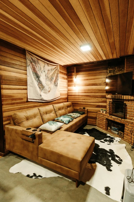 a room with wood walls, a large cow rug and a sectional couch