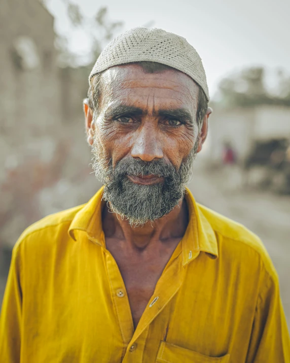 an old man with white hair and beard in yellow shirt