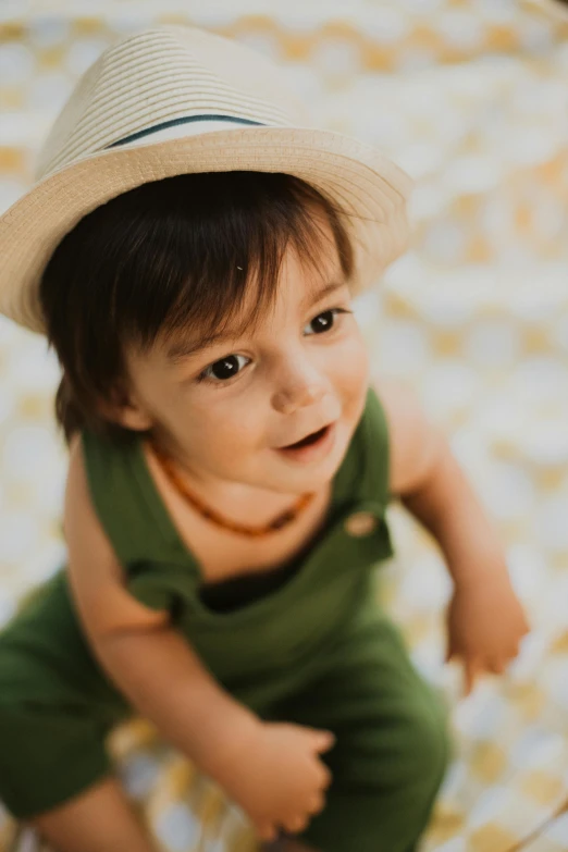 a baby with a hat sitting on top of a bed