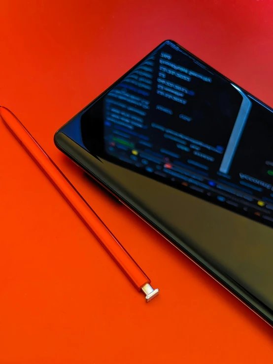 a tablet sitting on top of an orange surface with some pencils