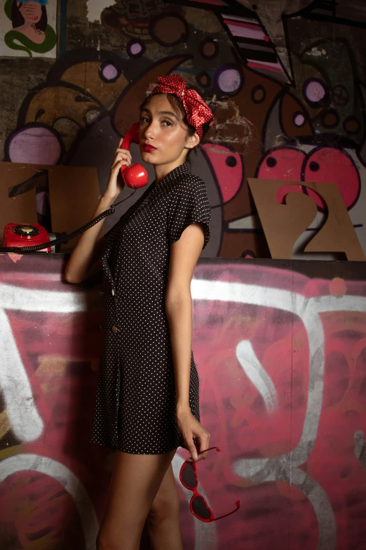 a girl in black and red is standing talking on the phone