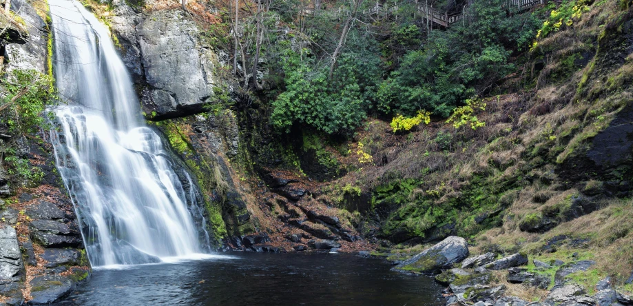 the small waterfall is next to a body of water