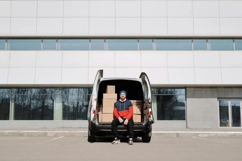 a man is sitting in the back of a van with boxes