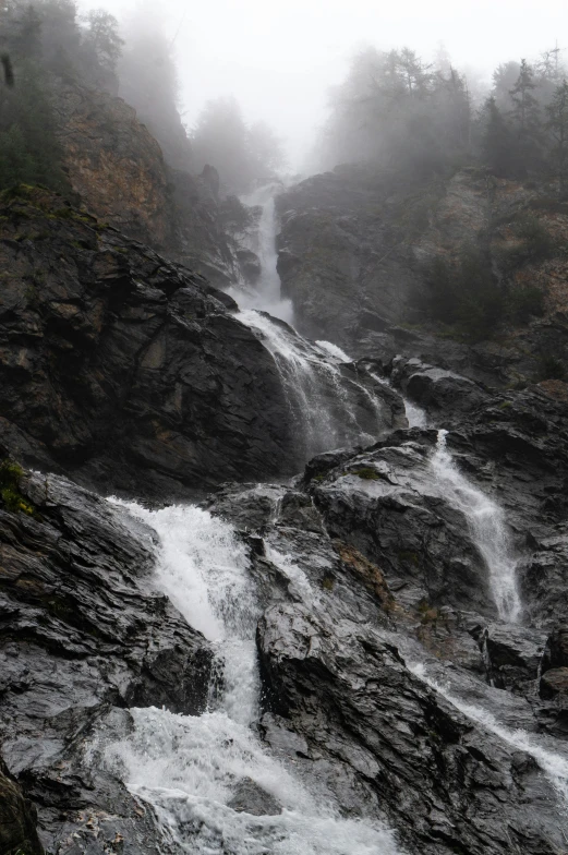 a waterfall falls from it in a misty sky