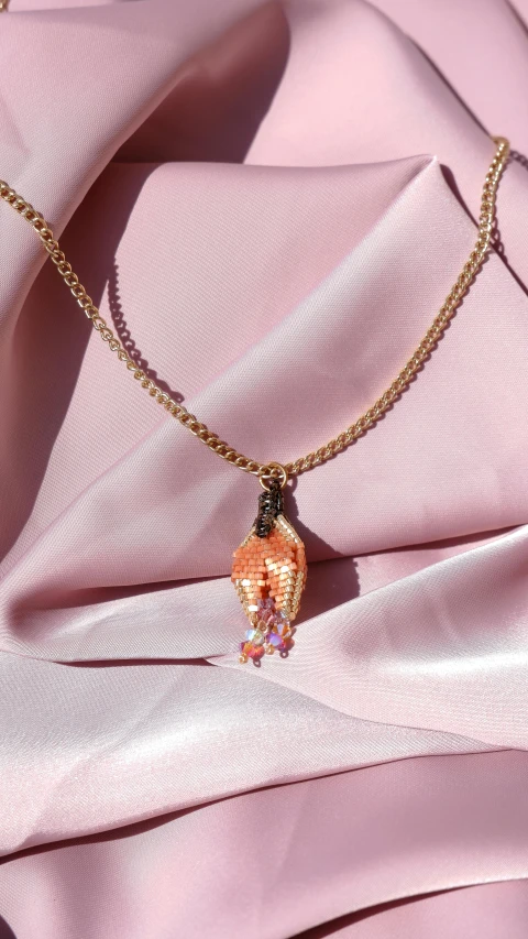 a necklace on a pink dress with a diamond charm