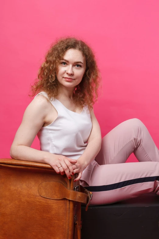 a young lady leaning on the top of a brown suitcase