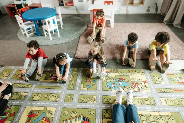 several children sitting on the floor playing with colorful rugs