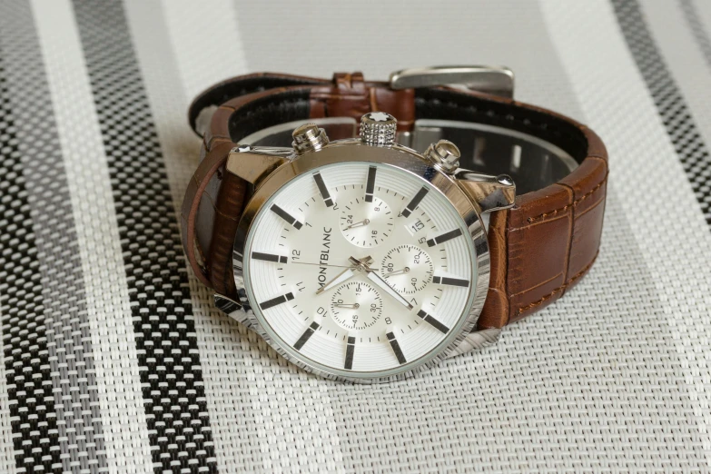 a watch on a leather strap on a white and black table cloth