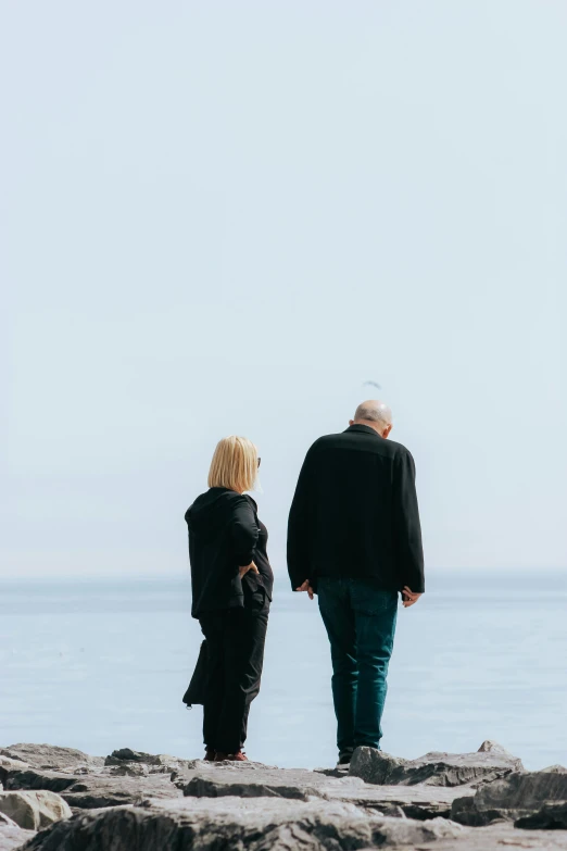 a man and woman are standing on the rocks