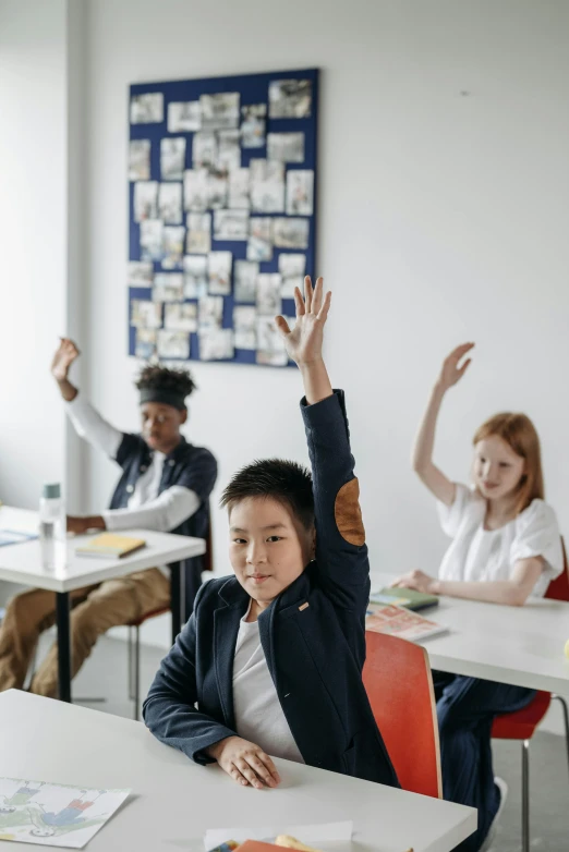 there is a boy sitting at the table raising his hands up