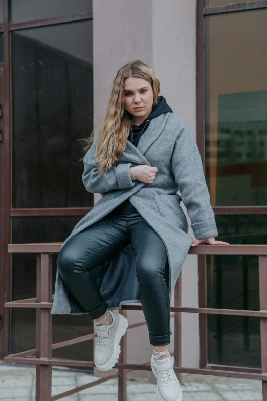 a woman sitting on a rail near a building