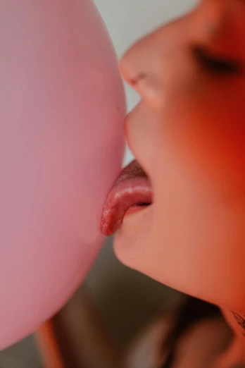 a young child opening a pink balloon to lick on it