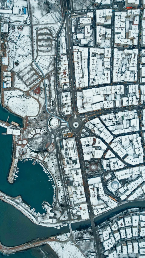 an aerial view of a snow covered city with several parking lots