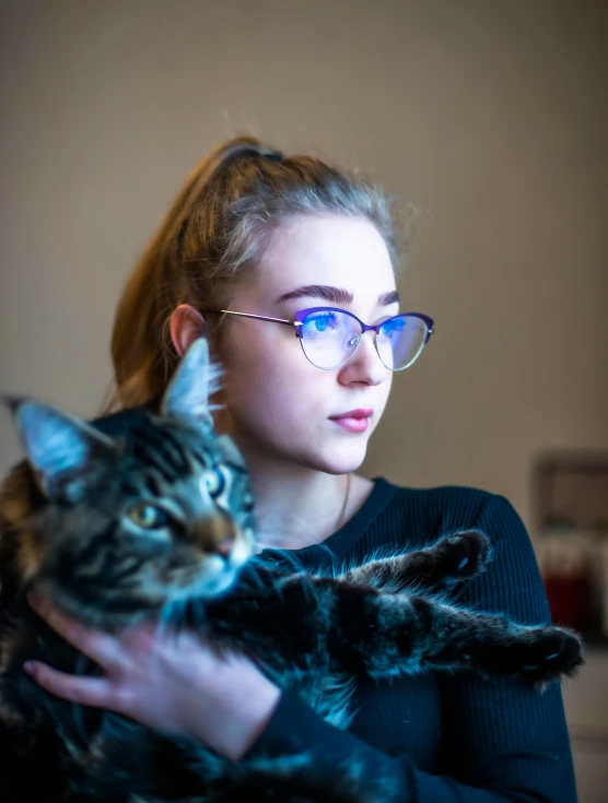 a woman in glasses holding a cat in her arms
