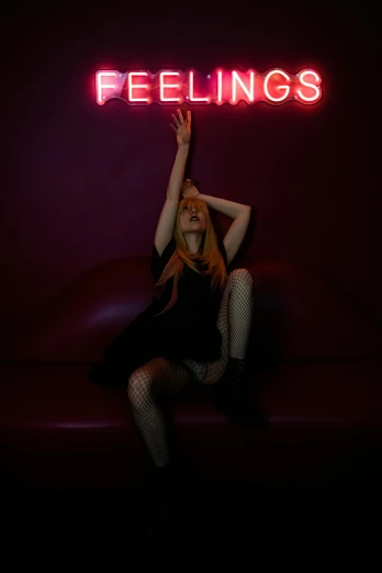 a lady is sitting down in front of a neon sign