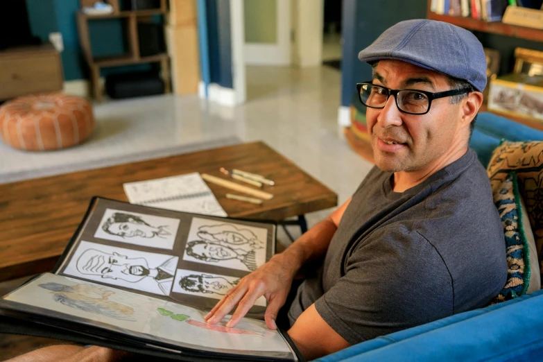 a man in a hat sitting on a couch with a laptop