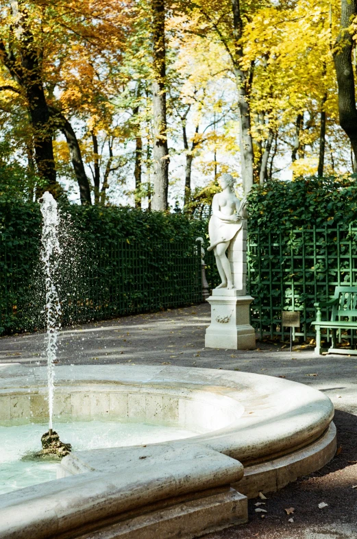 a fountain in the center of a park with a bench