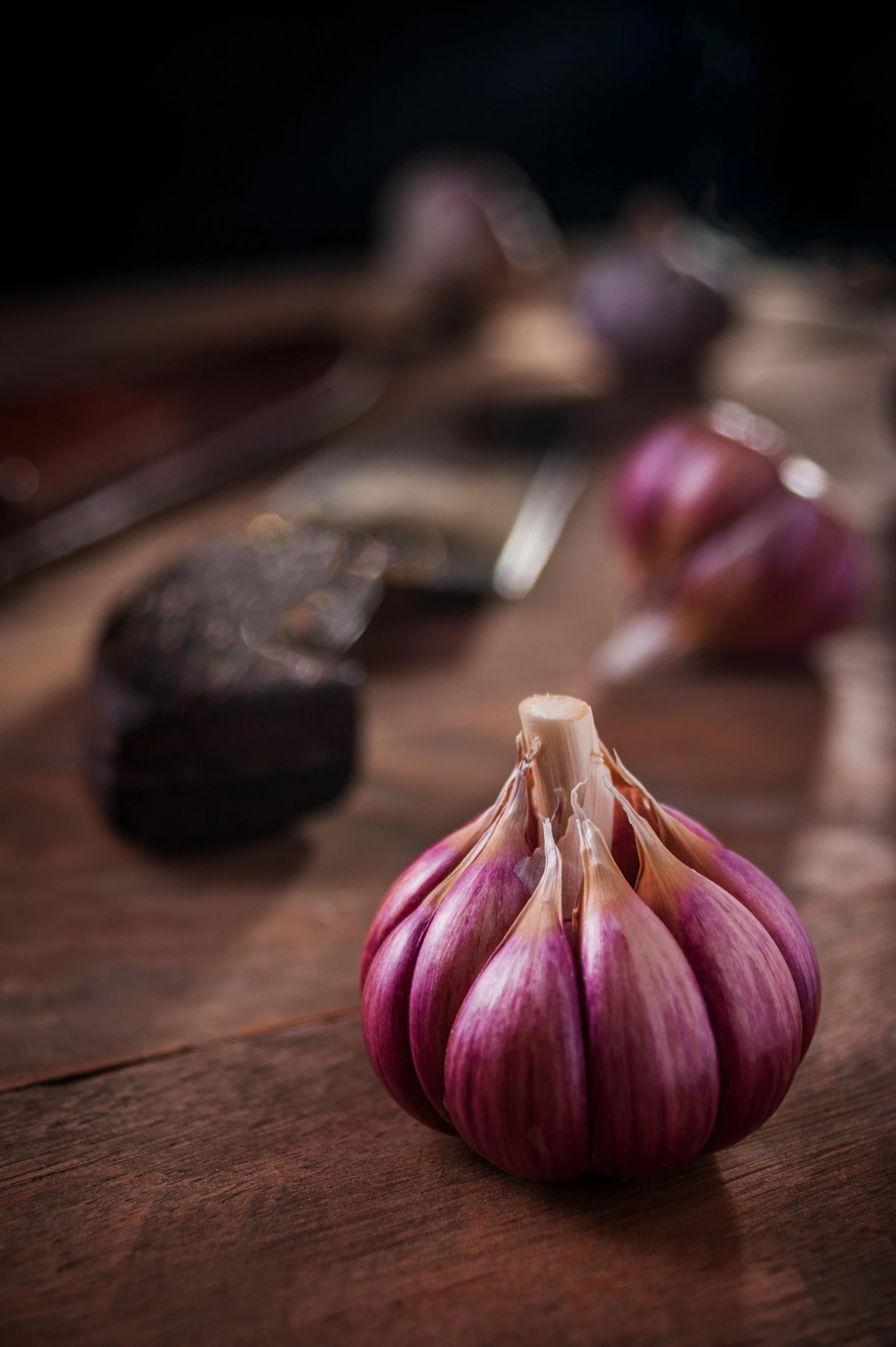 a single onion on a wooden table next to a spoon