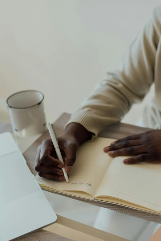 a man at a desk writing in a notebook with his hand on the page