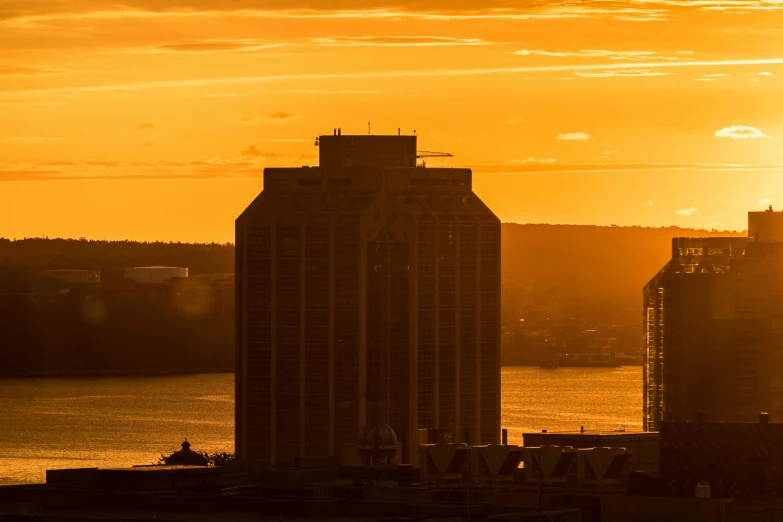 an orange and yellow sky shows the setting sun and buildings