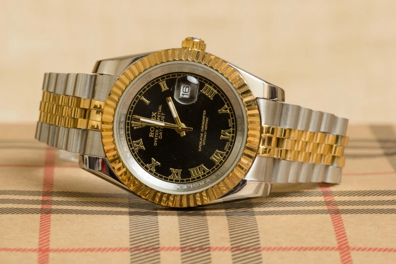 a rolex watch sitting on a checked table cloth