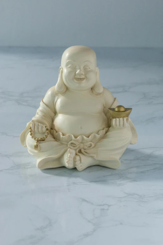 a ceramic figure of a buddha with a gold bowl in its hands