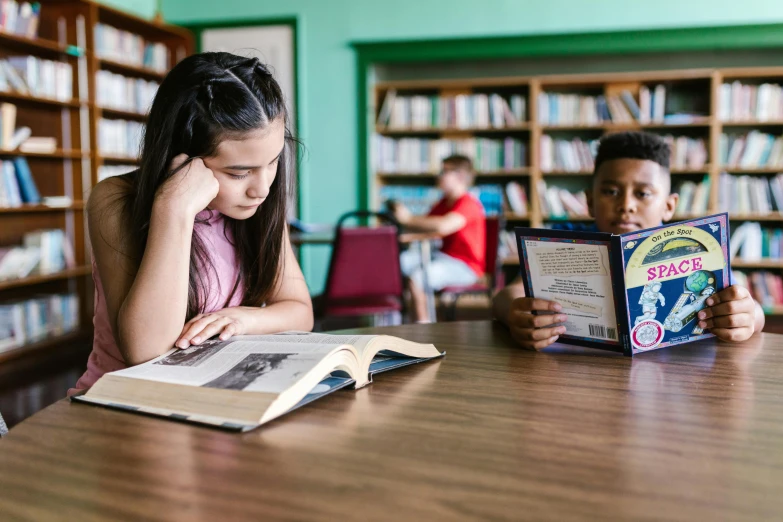 children look through a book while sitting at the table