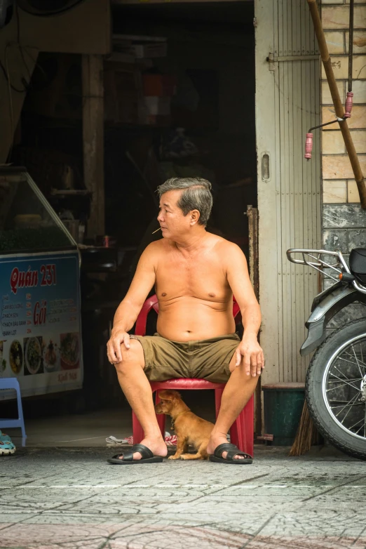 man sitting in chair next to dog on the ground