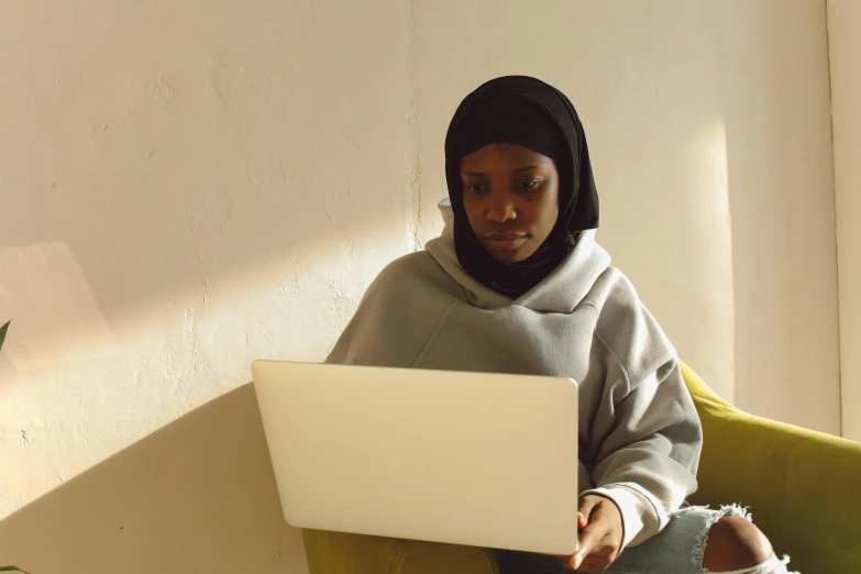 a woman in a black head scarf working on a laptop