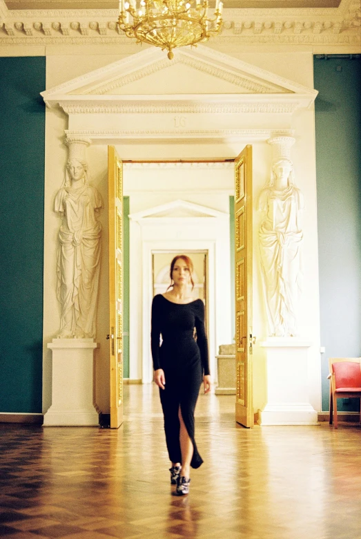 a woman in a long black dress walking away from the camera