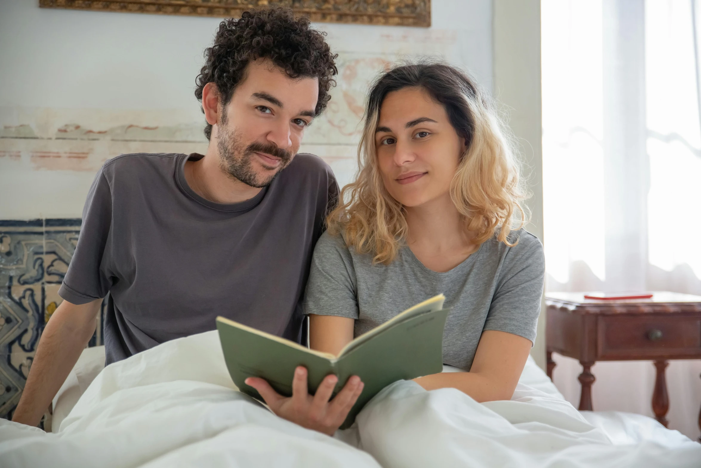 a man and woman sitting together in bed reading books