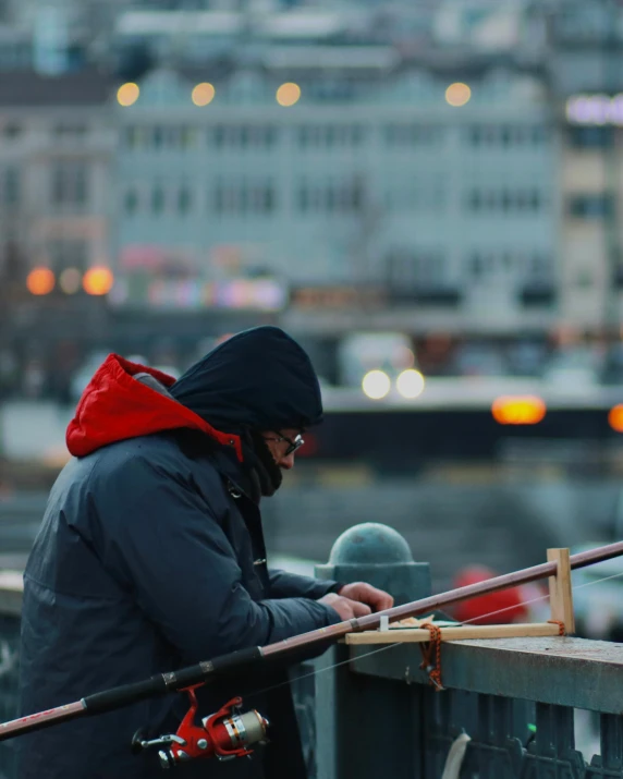 a man fishing in the city while wearing winter clothes