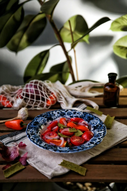 there is a blue plate of sliced tomatoes and herbs on a table