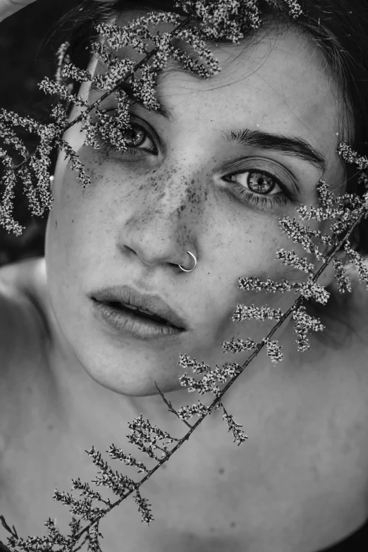 a young woman is holding a flower on her face