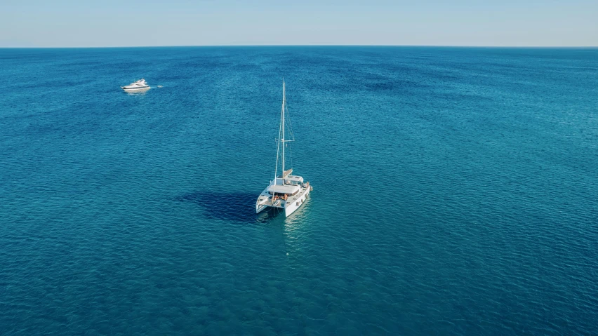 two white boats sailing in the middle of the ocean