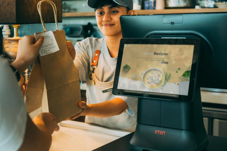 a person standing at a counter next to a computer