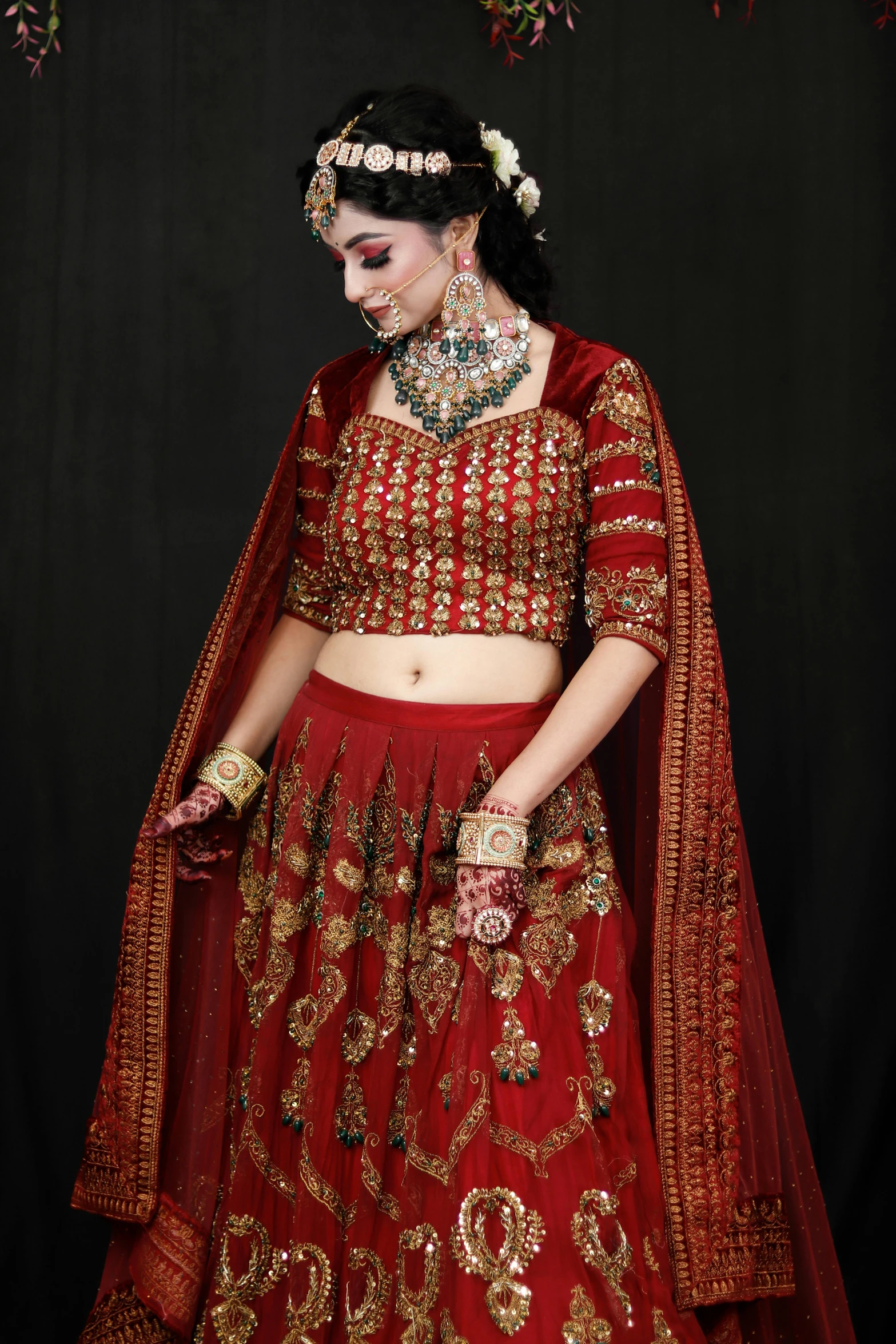 an indian bride wears an intricately decorated red bridal outfit