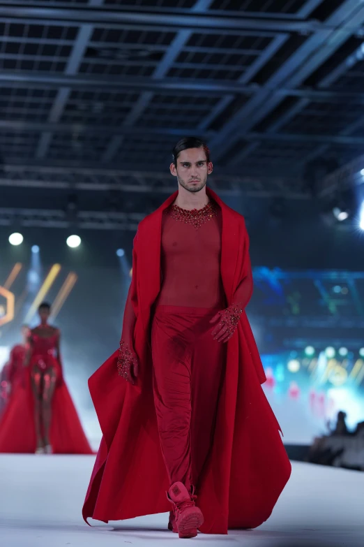 a man in red on the runway at a fashion show