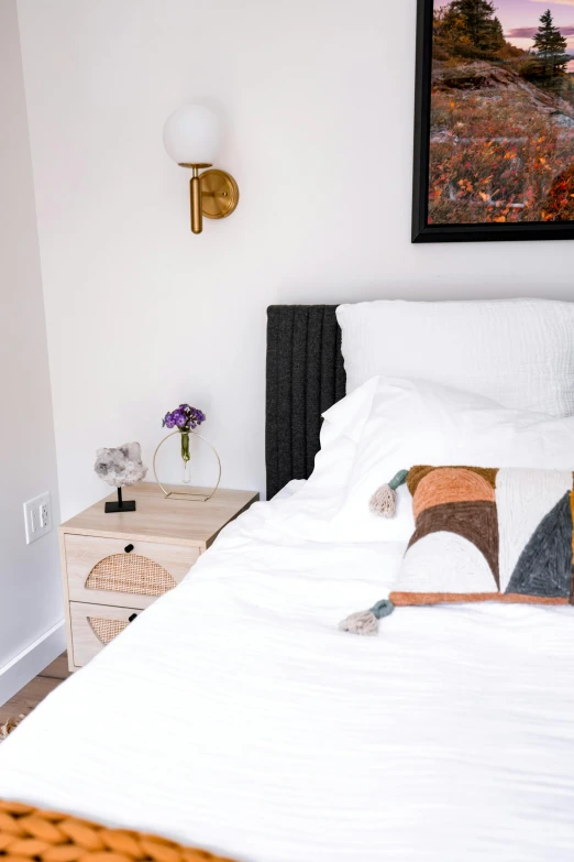 a bedroom with a bed and side table and a picture hanging above