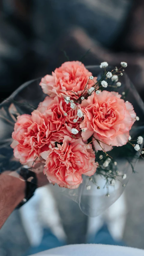 a person holding a bunch of flowers and wearing white shirt