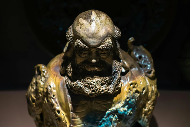 a statue with a beard and hair sitting in a dark room