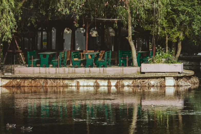 a restaurant with tables and green chairs on a pier