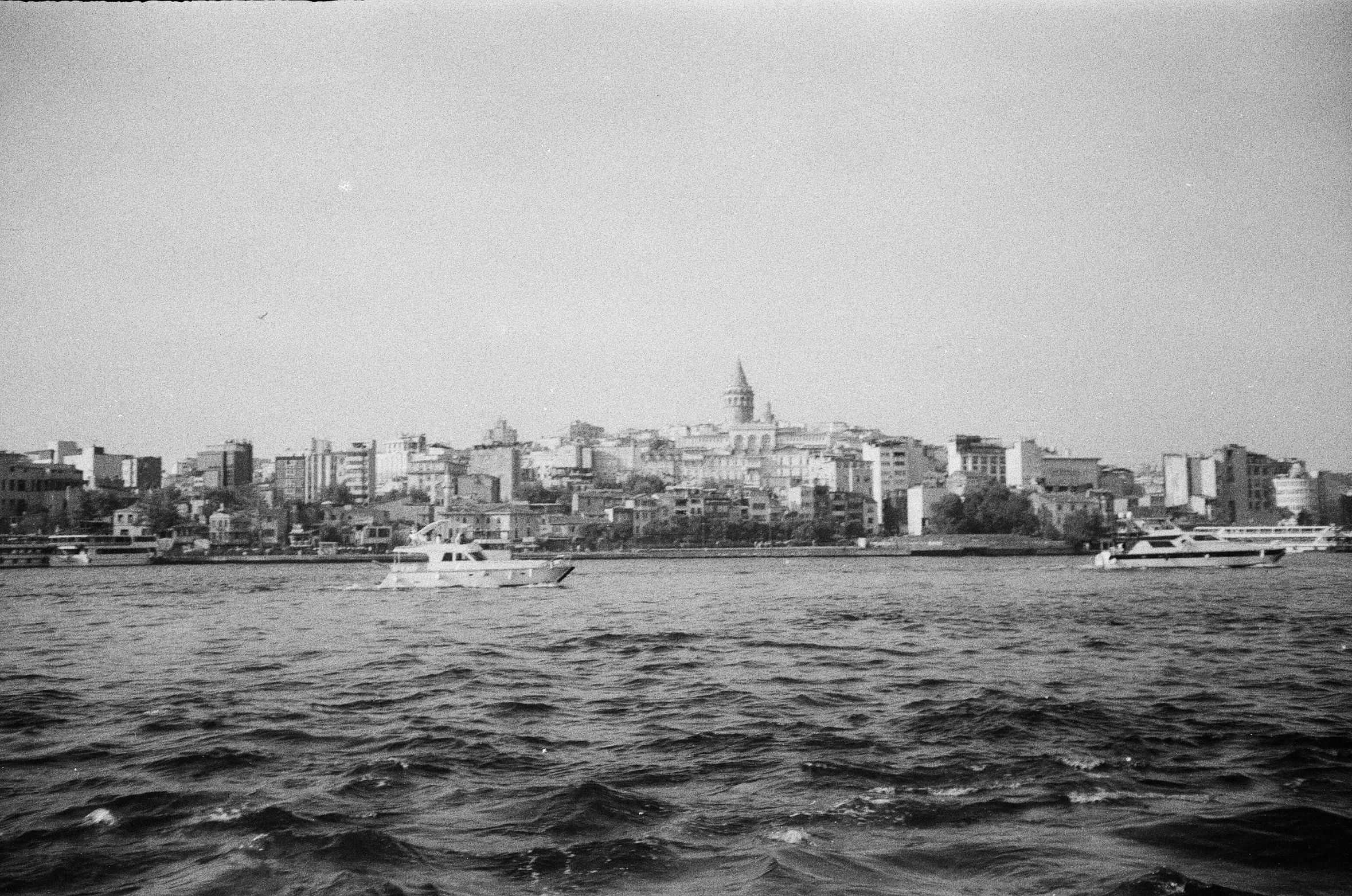 a boat in the middle of the sea with a city in the background