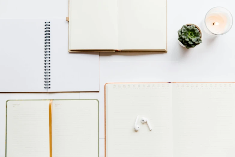 an open spiral notebook on a desk with candle and other office supplies