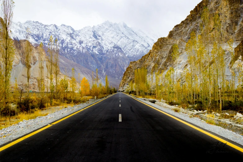 a empty road leading to a snowy mountain